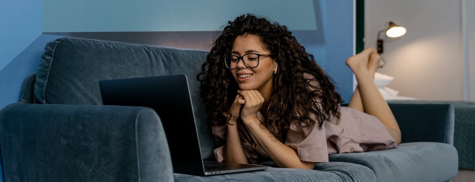 Young woman laying on couch working on her laptop